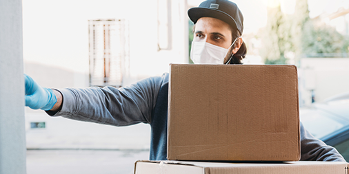 Delivery man wearing face mask and gloves is ringing the bell to deliver two cardboard boxes