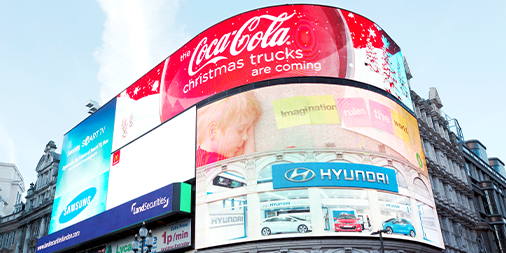 People walking below the electronic advertising display of Piccadilly Circus in London