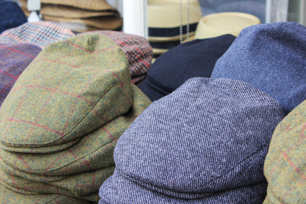 Variation men's newsboy cap stack in clothing store. Large group of hats are placed in a row, stack together. Many different textured & pattern.