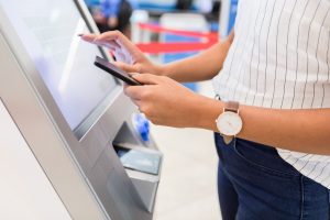 A woman stands at a kiosk in an airport as she gets her luggage tags