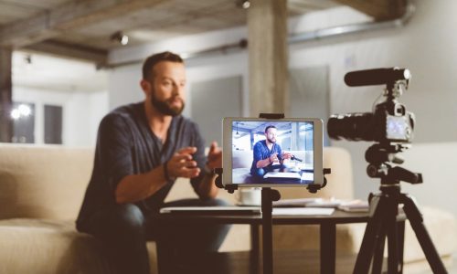 Young man making a video blog. Male vlogger recording content on digital camera.