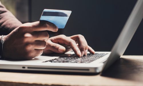 Men entering credit card information using laptop computer keyboard. Online shopping concept