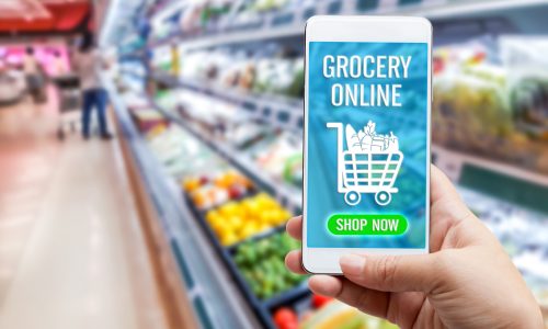 Online grocery shopping concept: Woman hand holding smart phone for ordering food onscreen with icon media on supermarket background. Business and technology for lifestyle in city.