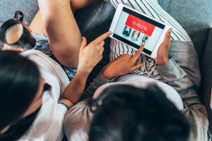 Two female friends drinking coffee and shopping online