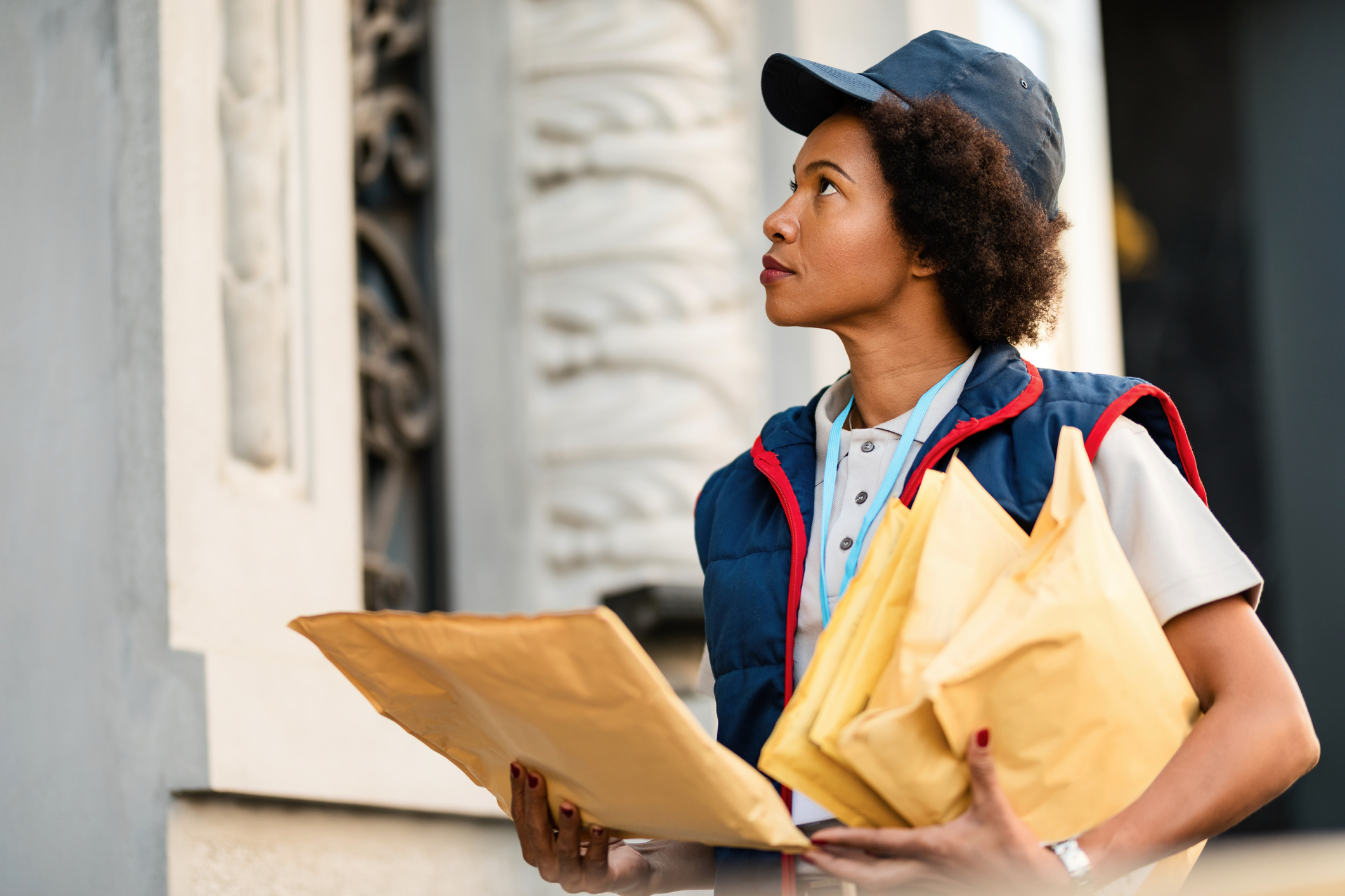 Black postwoman delivering mail in residential district.