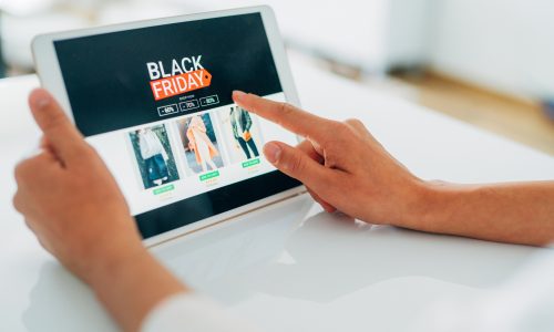 Close-up shot of a young woman holding a digital tablet and shopping online on Black Friday at home.