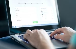 Person typing on laptop with purchase form on screen