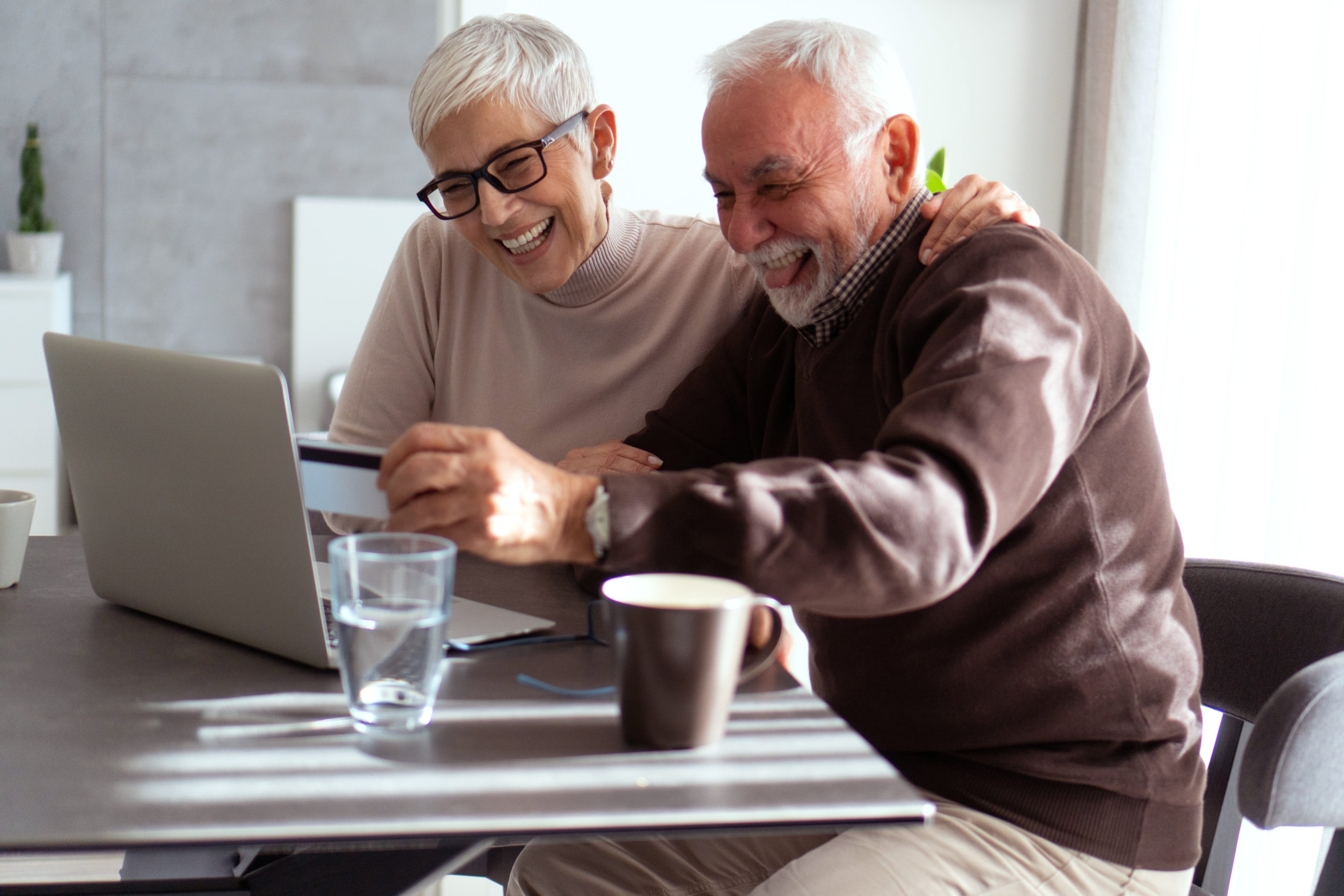 Senior people are shopping online by using laptop and credit card.