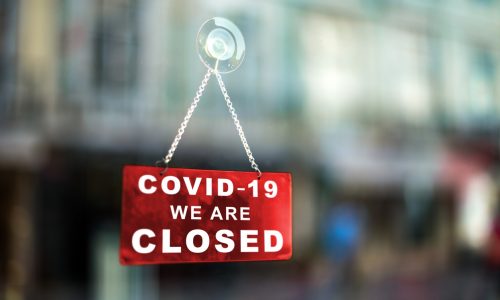 Red sign on window informing that the business is closed due to covid-19