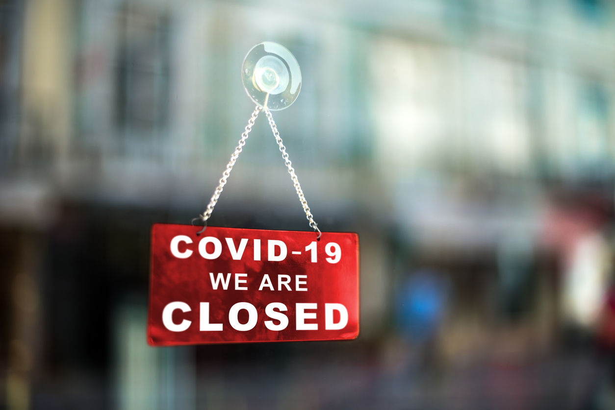 Red sign on window informing that the business is closed due to covid-19