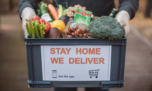 Delivering food ordered online while in home isolation during quarantine. Stay home we deliver sign on box.