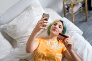 Young woman with colored hair is shopping online with a credit card