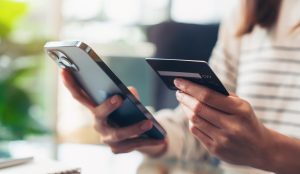 Woman holding credit cards and using smartphone for shopping online