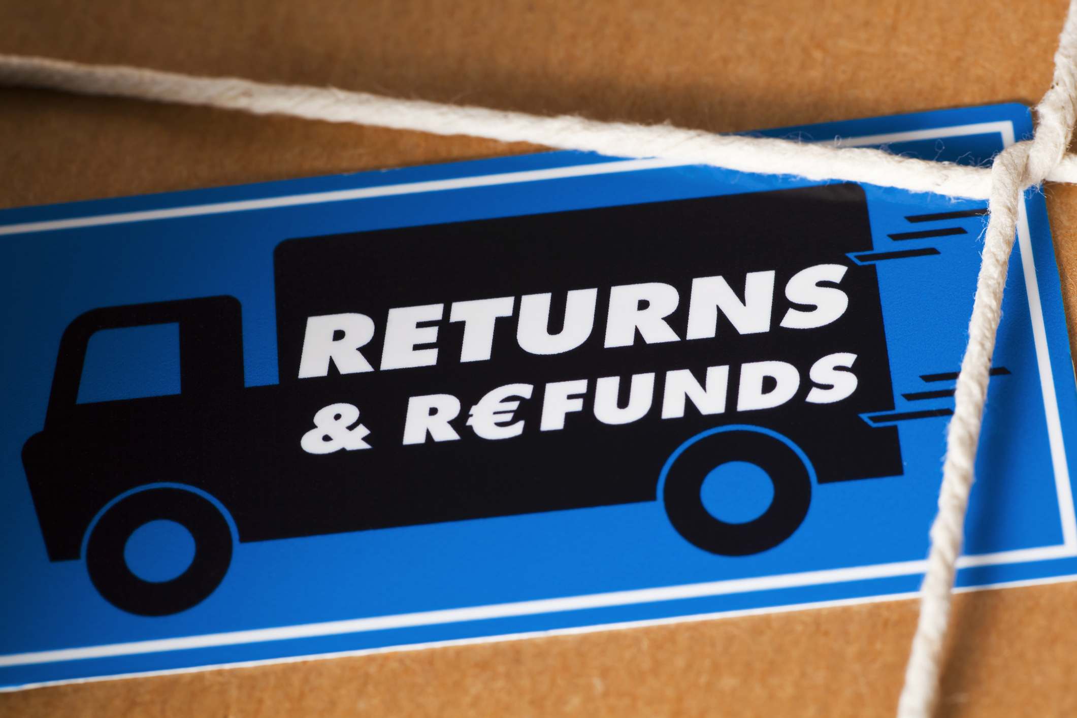 Return the goods by a courier for a Euro Refund. Close up of a brown paper parcel, tied with string and a Return & Refunds sticker.