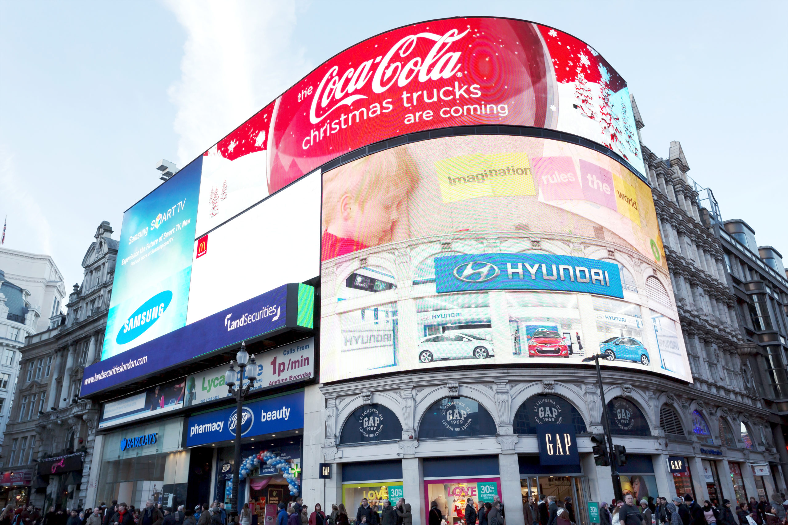 People walking below the electronic advertising display of Piccadilly Circus in London