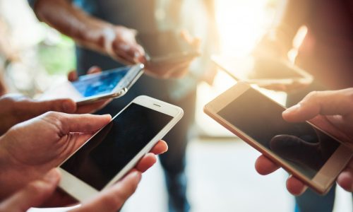 Shot of a group of colleagues using their cellphones together in an office