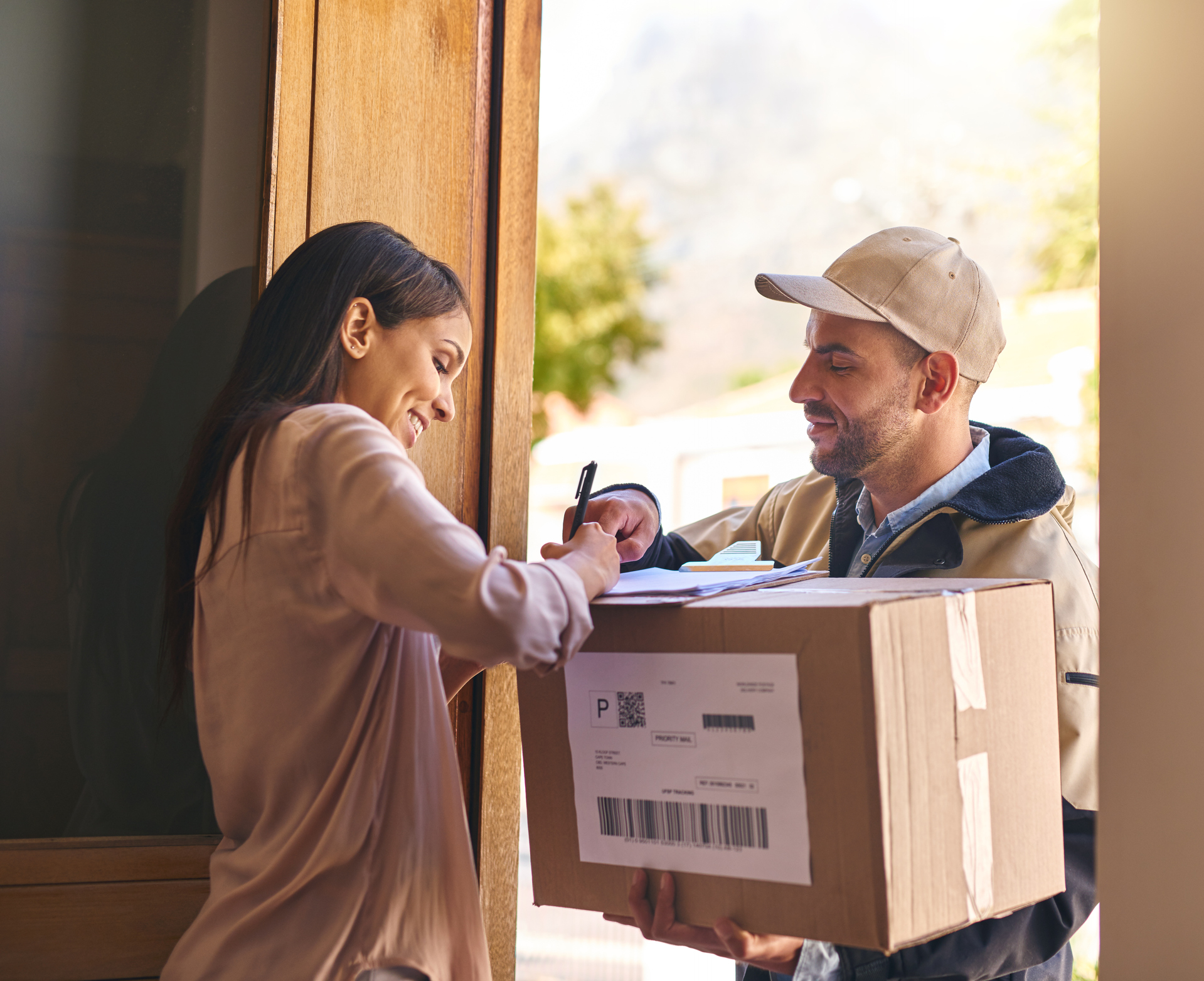 Shot of a young woman signing for her delivery from the courier