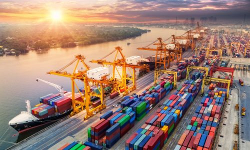 Container Cargo ships and containers in shipyard at sunrise.